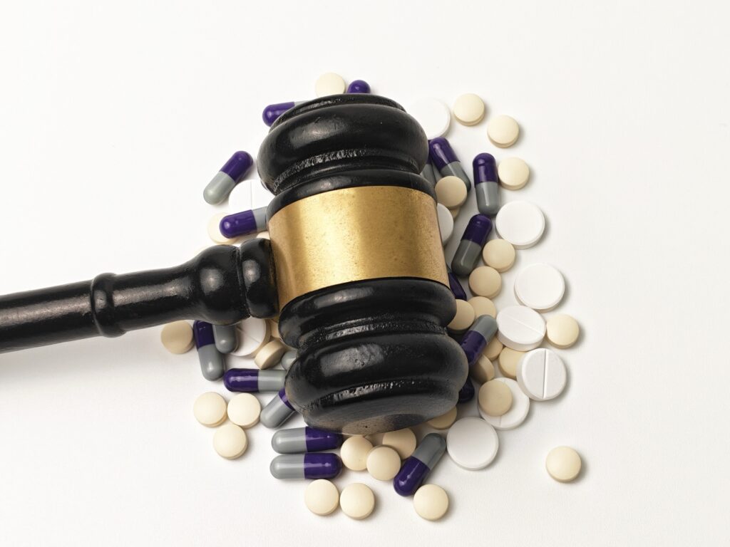 Sędzia gavel o pigułkach i kapsułkach medycznych symbolizujących prawo farmaceutyczne prawo farmaceutyczne sprawy sądowe dotyczące leków niewłaściwe praktyki i sprawiedliwość